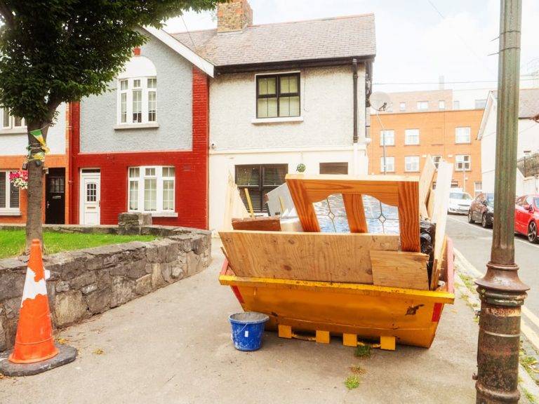 Maxi skip filled with household waste outside of houses